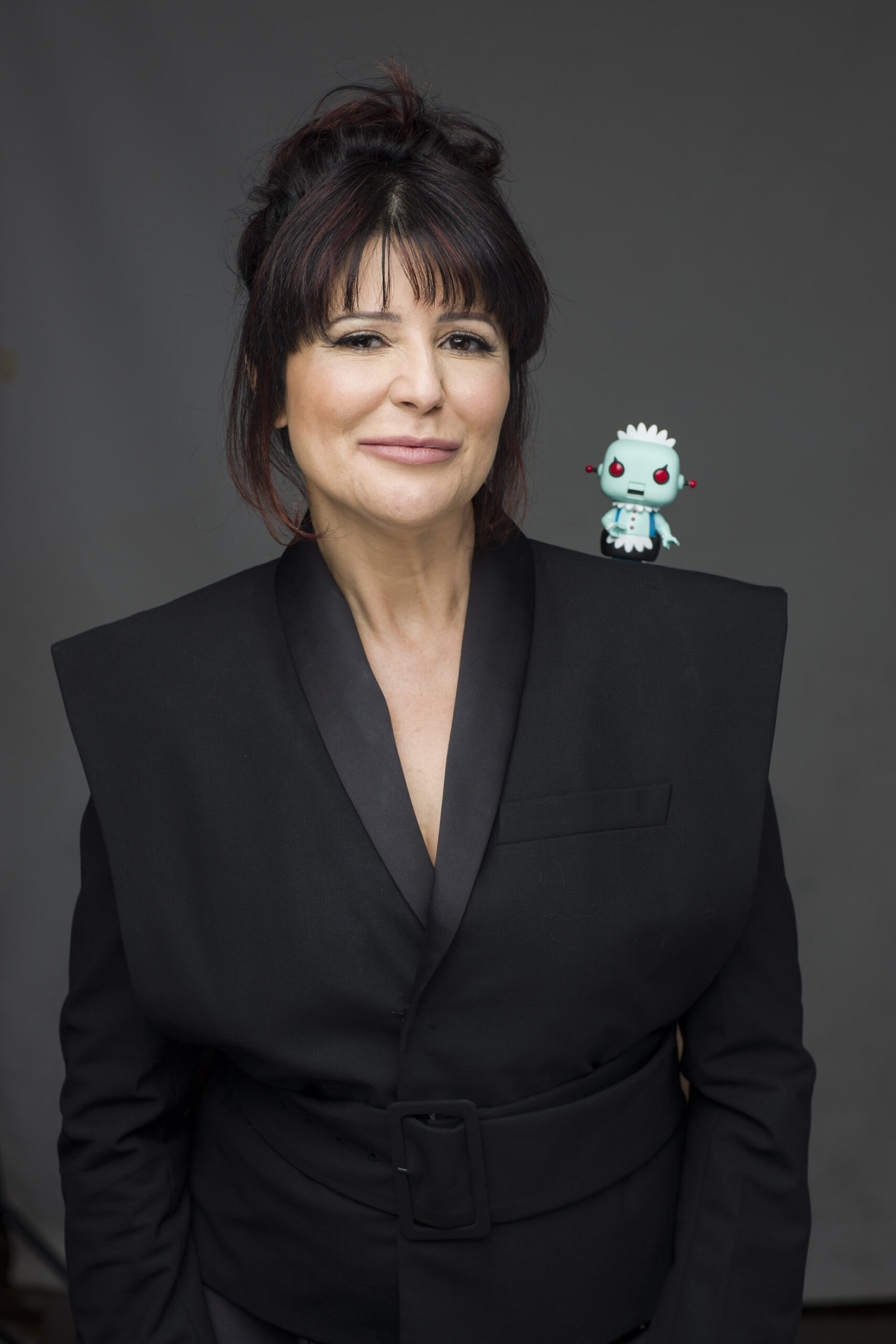 Denise está olhando pra frente com um robozinho no ombro